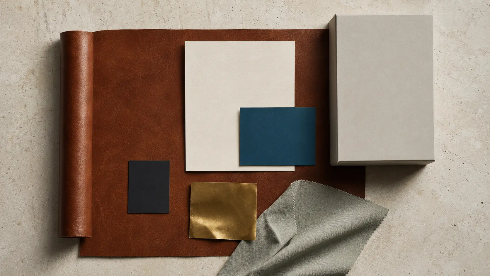 Système de matières acajou, ivoire, bleu pétrole, olive doré, charbon et textile gris sauge pour identité visuelle et impression