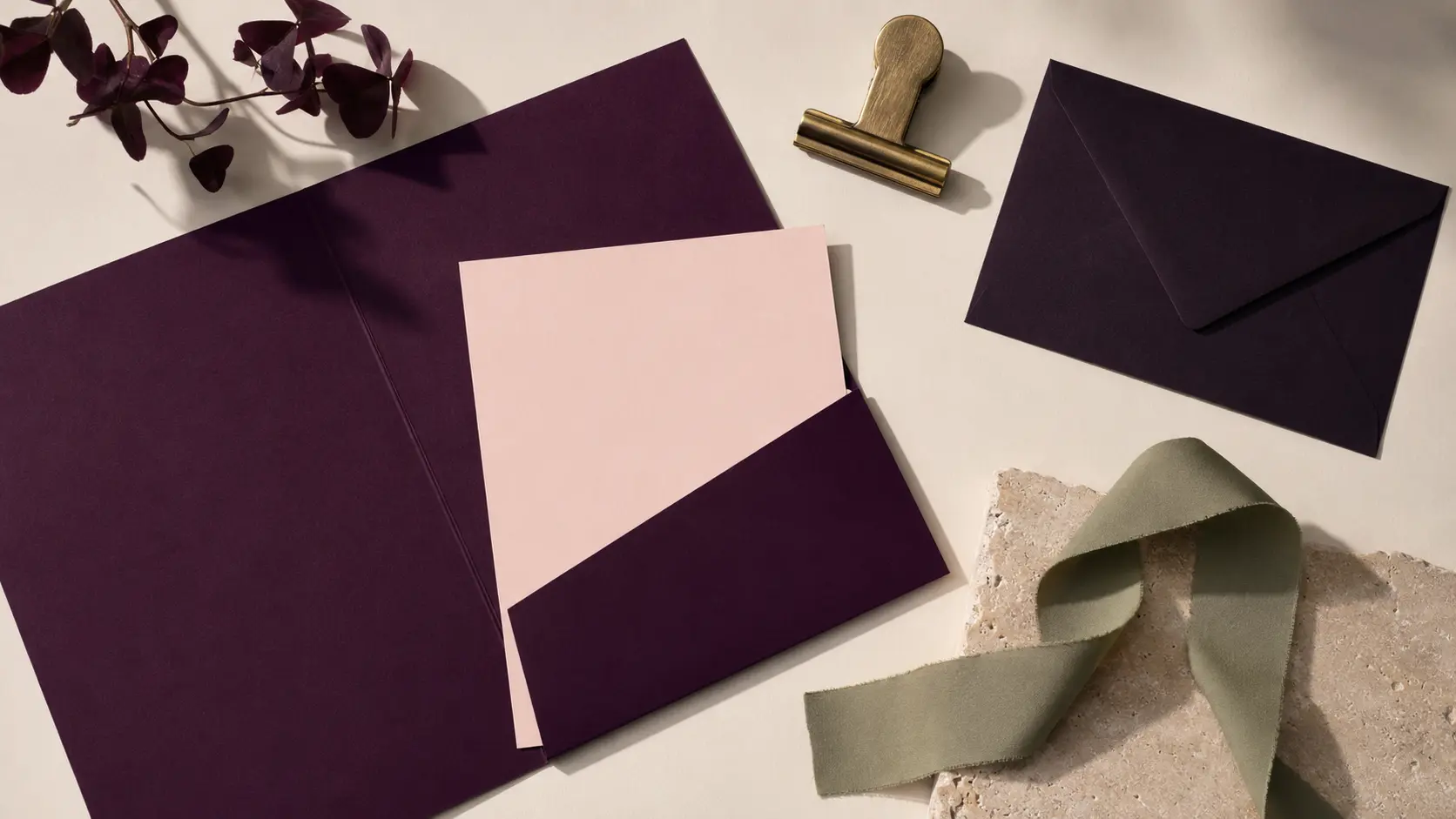 Palette d’application aubergine avec papeterie rose poudré, ruban sauge, laiton et enveloppe prune noire