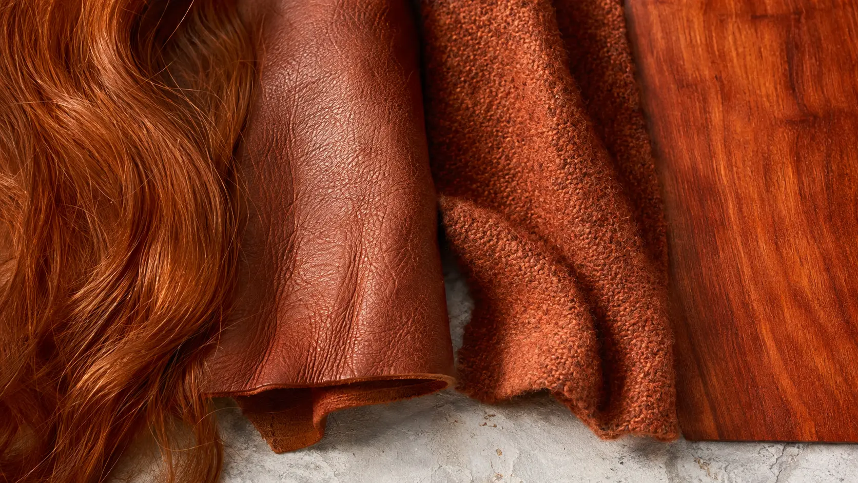 Étude de matières auburn : mèche de cheveux, cuir grainé, laine cuivrée et placage de bois rouge