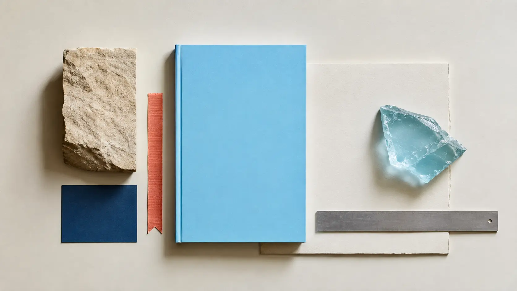 Palette d’application azur avec carnet bleu clair, papier ivoire, bleu encre, ruban corail, pierre sable et métal