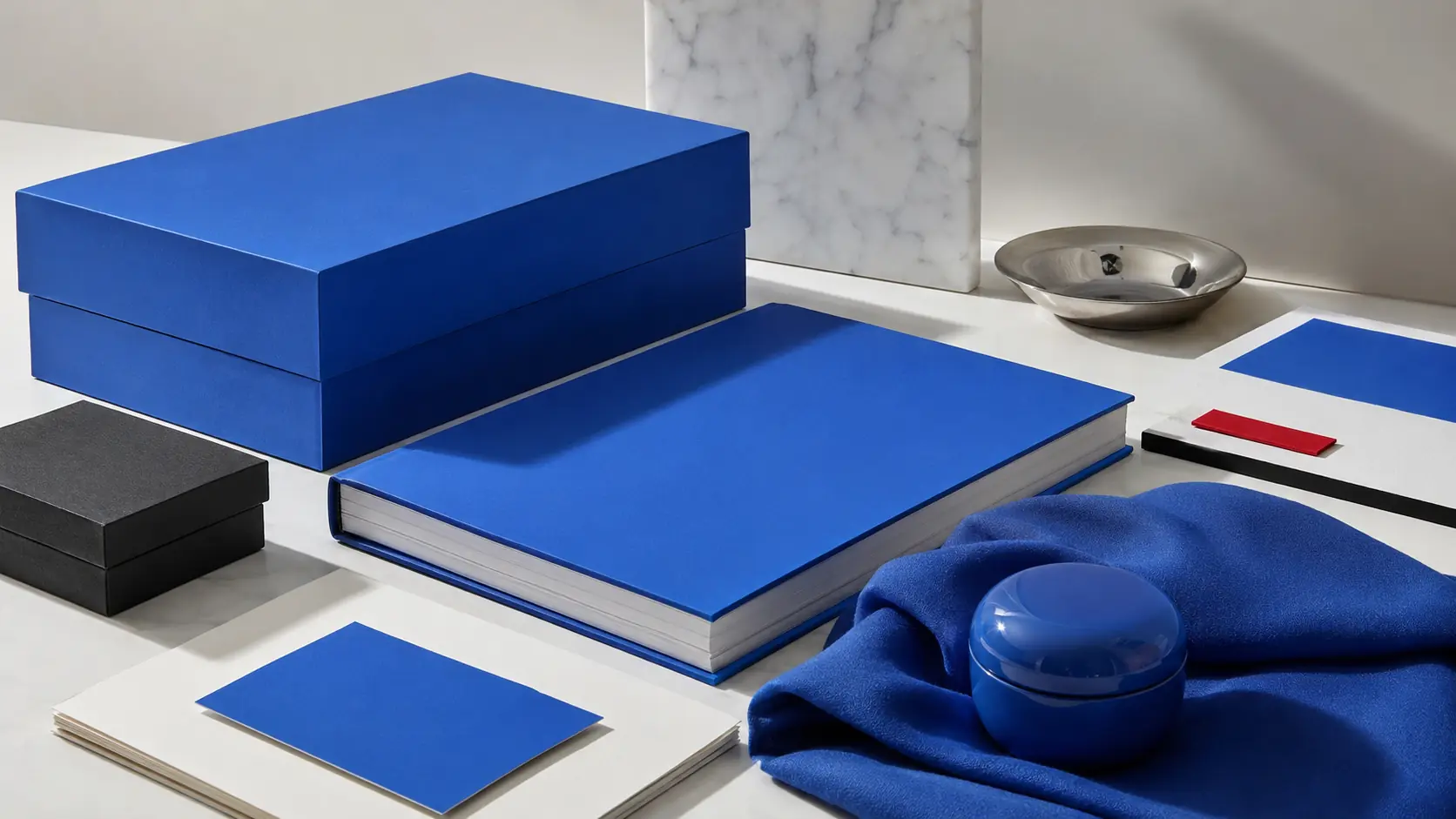 Système d’application bleu roi avec boîte, carnet, papiers blancs et graphite, textile, métal argenté et accent rouge