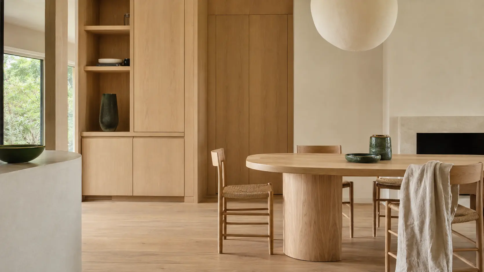 Intérieur couleur bois avec salle à manger en chêne clair, lin, enduit ivoire, céramique vert forêt et détails charbon