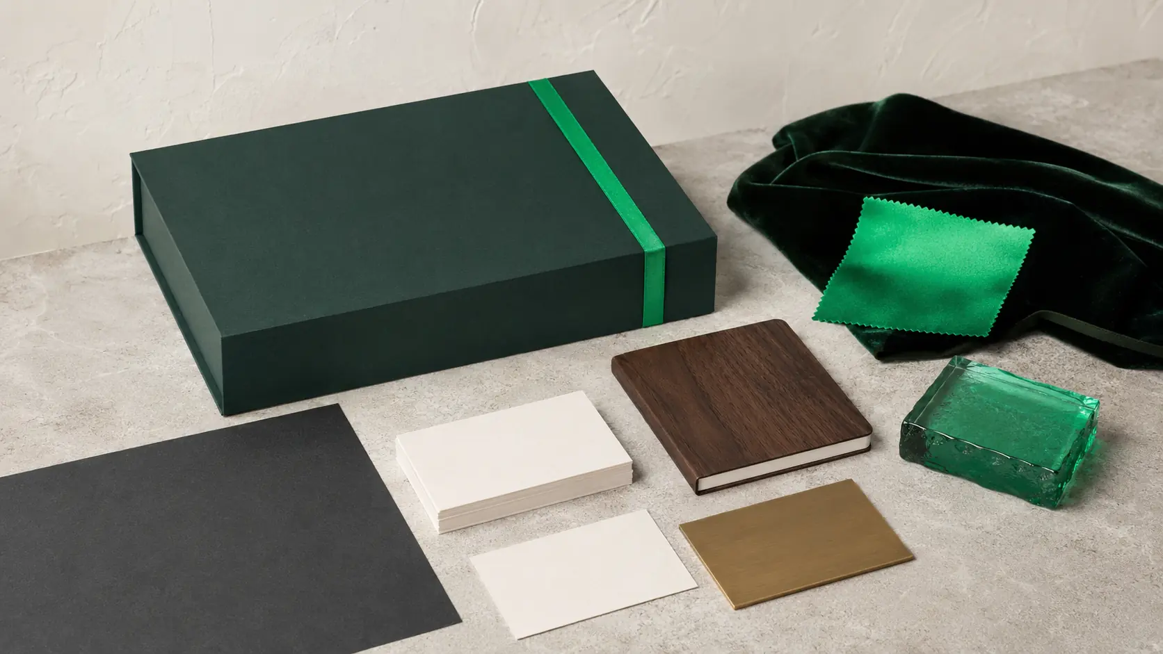 Système d’application émeraude avec boîte vert profond sans marque, cartes ivoire vierges, carnet en noyer, papier charbon, verre vert transparent