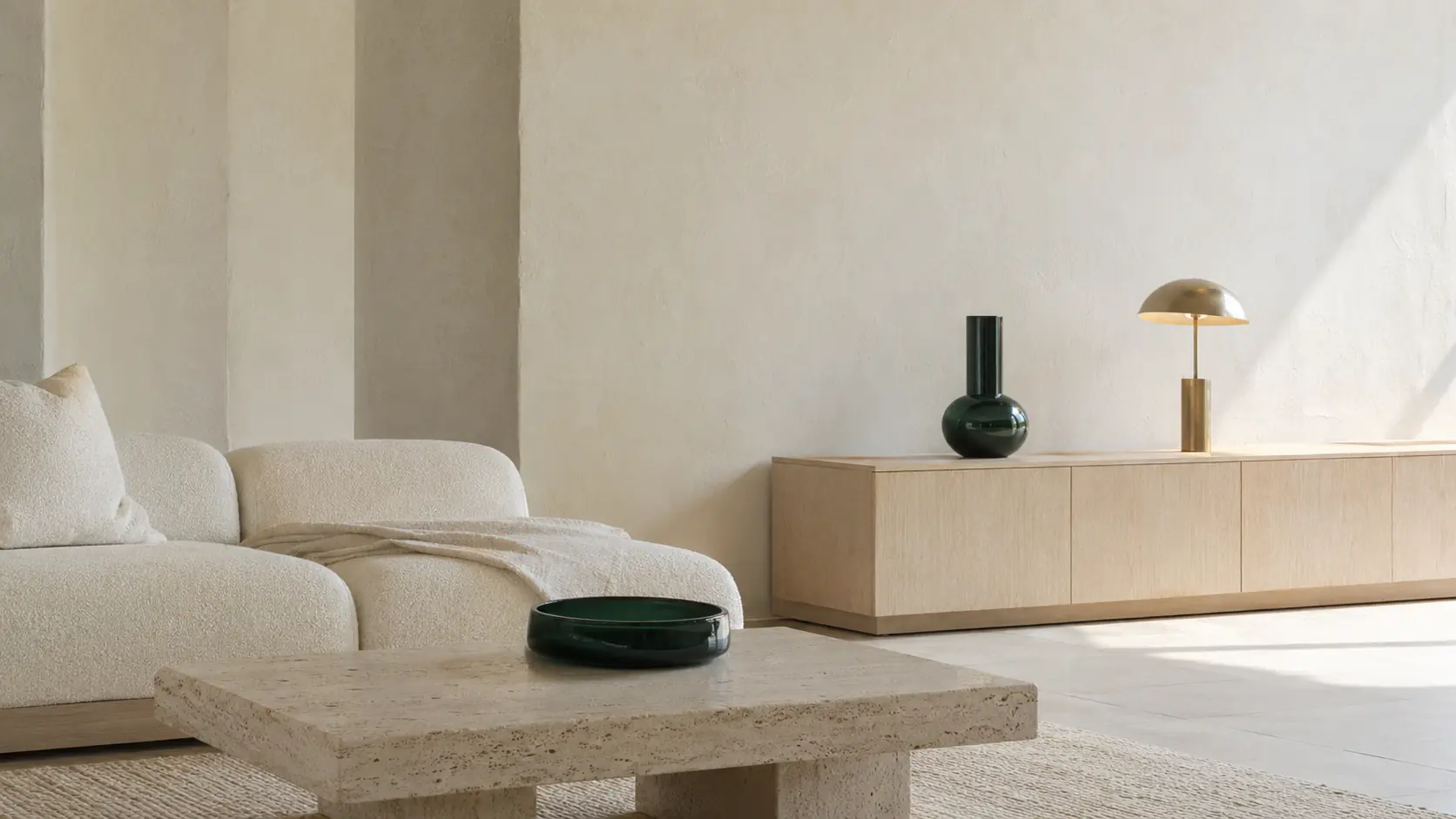 Intérieur contemporain très lumineux avec murs ivoire à la chaux, canapé en lin et laine bouclée, table en travertin clair, menuiseries en frêne