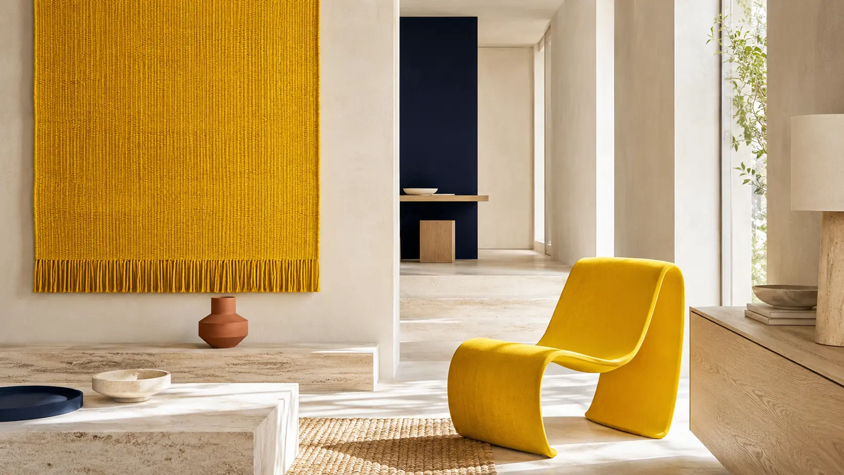 Intérieur contemporain lumineux avec grand panneau textile jaune safran, fauteuil safran, murs ivoire, mobilier en chêne, sol travertin, objet bleu nuit et petite céramique terre cuite