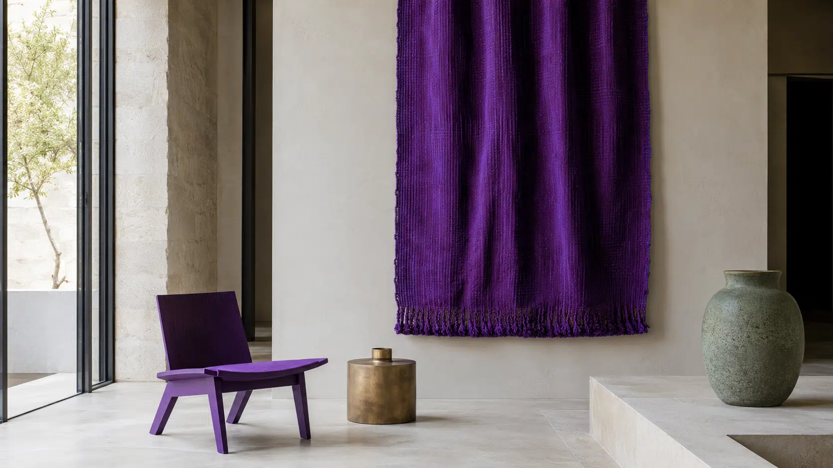 Intérieur contemporain lumineux avec grand panneau textile violet sombre, assise violette, calcaire clair, éléments encre, petit objet en laiton mat et accent vert lichen